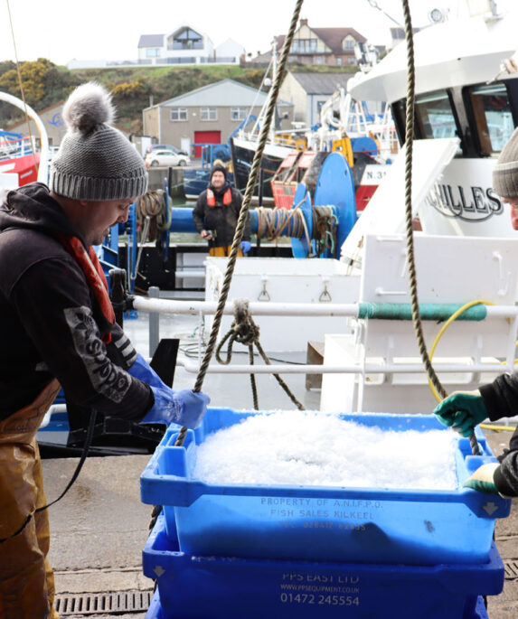 Two fishermen landing a fish box from a Scottish trawler